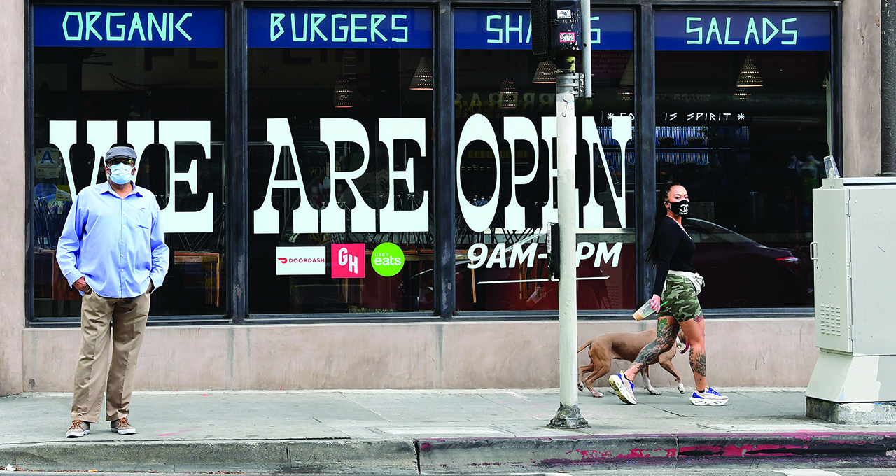 Pedestrians wear protective masks in front of a restaurant in Los Angeles on May 12, the same day California Gov. Gavin Newsom announced guidelines for reopening restaurants for dine-in service. (Frederic J. Brown/AFP via Getty Images)